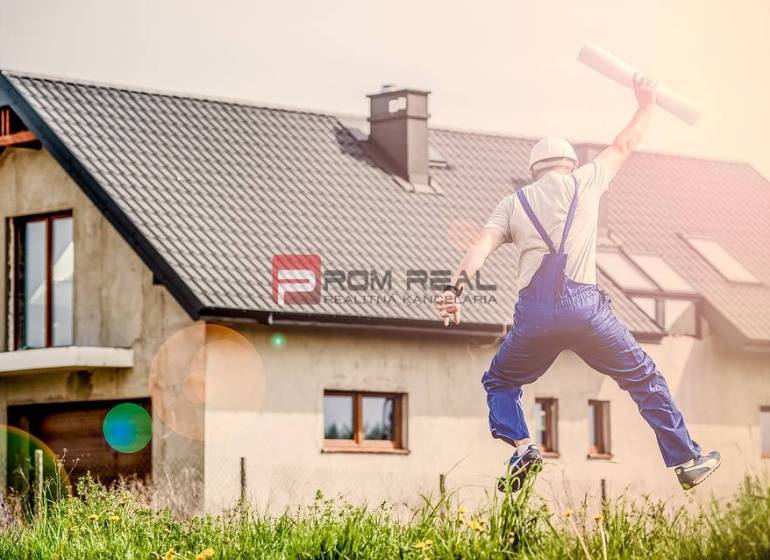 Der Bauarbeiter springt glücklich vor dem Haus und hält die Baupläne. Bau und Einzimmerwohnung.