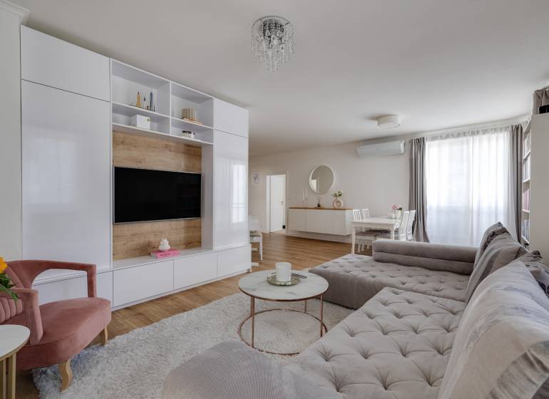 Wohnzimmer in einer 3-Zimmer-Wohnung mit bequemer Couch, TV-Wand und Esstisch.