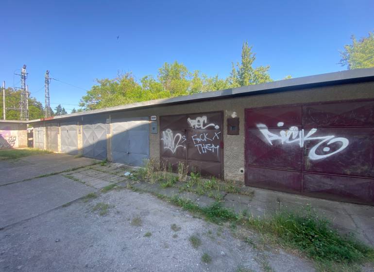 Garagen in Zvolen mit Graffiti auf den Toren, umgeben von Grünflächen und Betonflächen.
