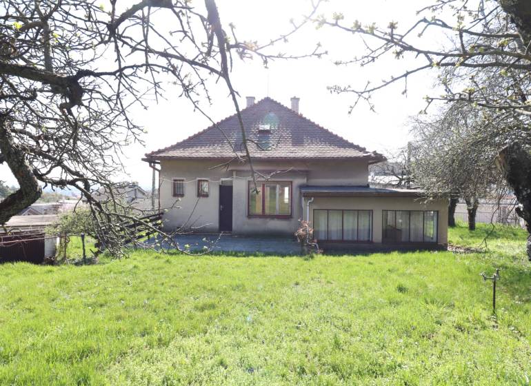 Ein Einfamilienhaus in der Jalovcova-Straße in Bratislava - Koliba, umgeben von einem Garten und Bäumen.