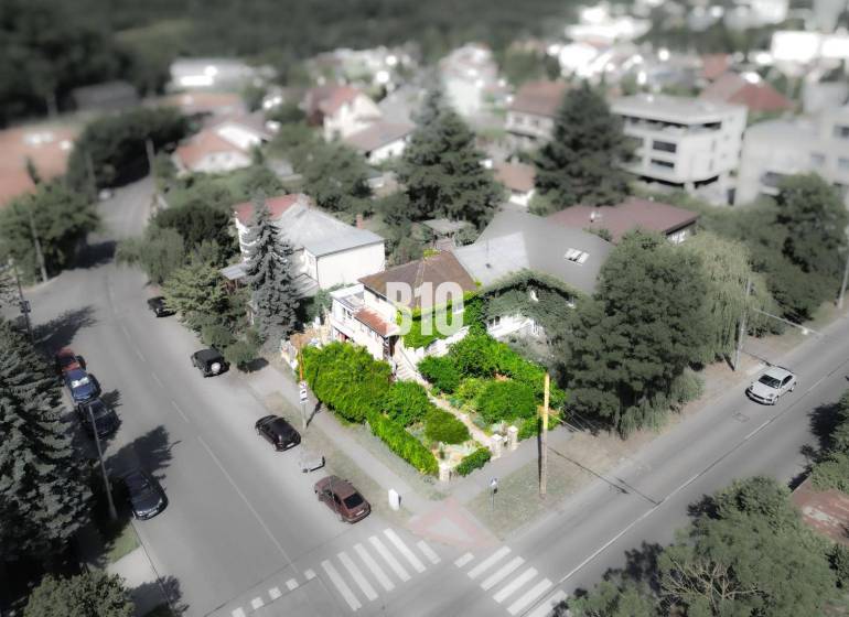 Ein Einfamilienhaus in der Gegend von Bratislava - Altstadt, umgeben von Grünflächen und einer Straße mit Autos.