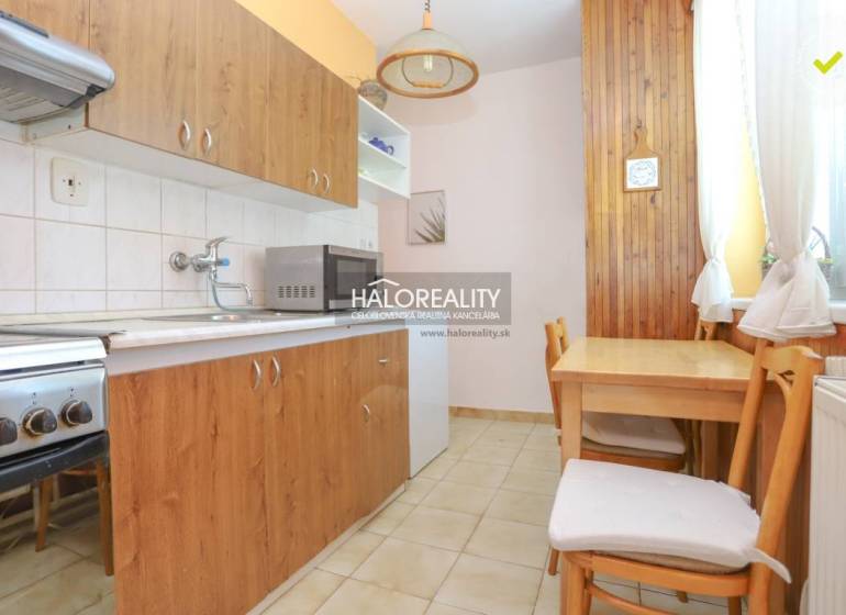 Küche in einer 3-Zimmer-Wohnung mit Holzmöbeln, Herd und Mikrowelle.