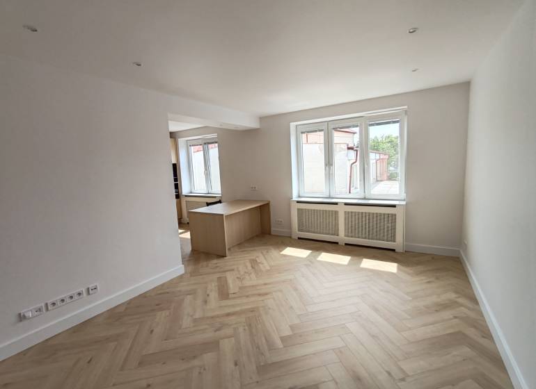 Helles Wohnzimmer in einer 2-Zimmer-Wohnung mit Holzboden und Fenstern.
