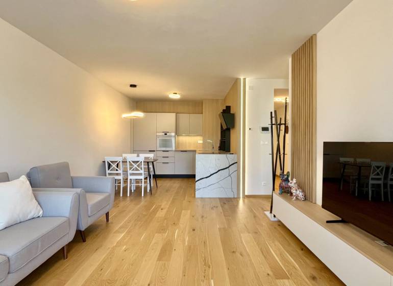 Wohnzimmer in einer 2-Zimmer-Wohnung mit Holzboden, Sofa und Fernseher.