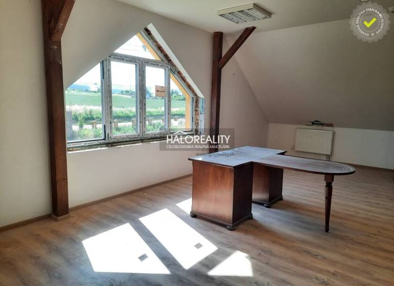 Dachzimmer mit Holztisch und großem Fenster in einer 2-Zimmer-Wohnung.