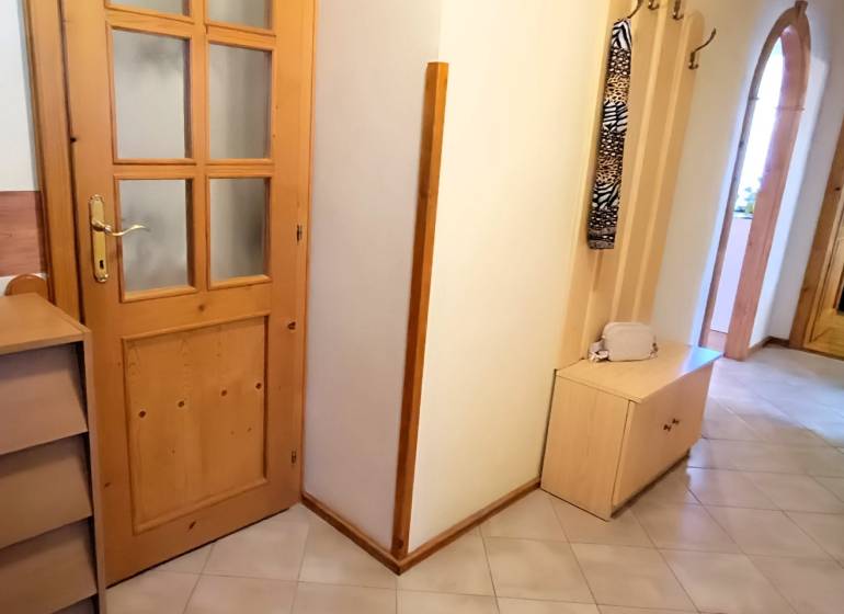 Der Flur in der 3-Zimmer-Wohnung mit Holzmöbeln und Dekoration in der Vase.