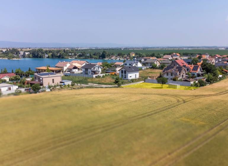 Grundstücke - Wohnen in Dunajská Lužná mit Blick auf den See, Häuser und Felder.