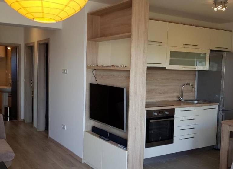 Küche in einer 3-Zimmer-Wohnung mit eingebauten Geräten und einem Fernseher an der Wand.