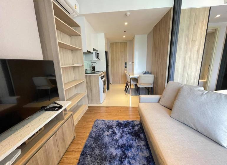 Wohnzimmer in einer Zweizimmerwohnung mit Sofa, Fernseher und Essecke.