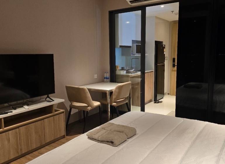 1-Zimmer-Wohnung mit TV, Bett, Tisch, Küchenzeile und Klimaanlage.