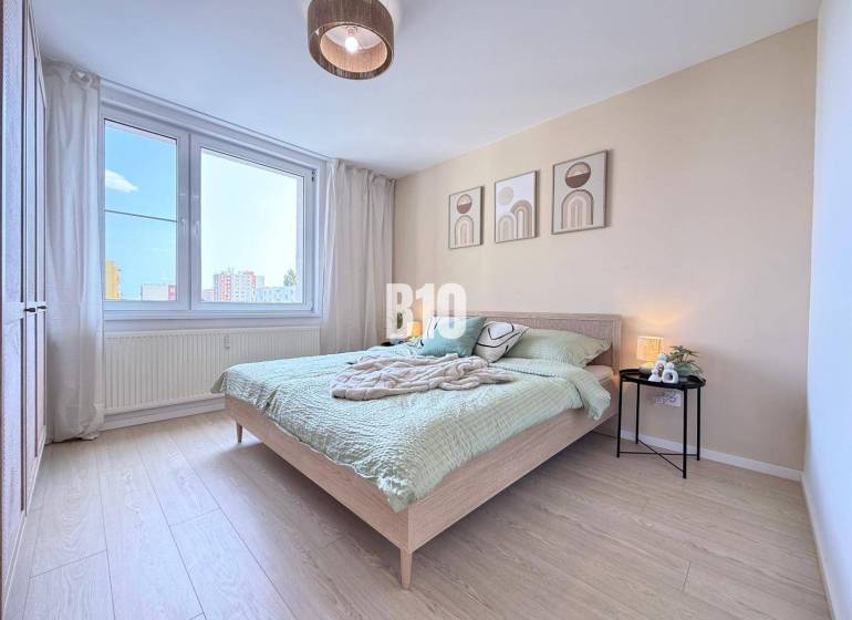 Ein Schlafzimmer in einer 3-Zimmer-Wohnung mit moderner Einrichtung und großem Fenster.