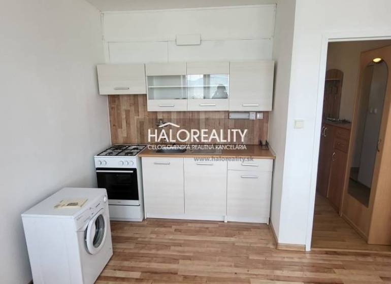 Küche in einer Einzimmerwohnung mit Herd, Geschirrspüler und Schränken, Holzboden.