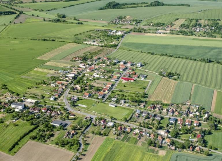Luftaufnahme eines Dorfes zwischen Feldern in Kamenné Kosihy, ideal für Gewerbegrundstücke.