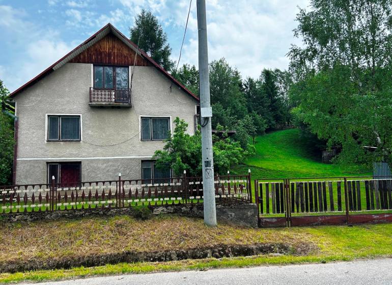 Ein Einfamilienhaus in Veľká Lesná mit gepflegtem Garten und Rasen, umgeben von Bäumen.