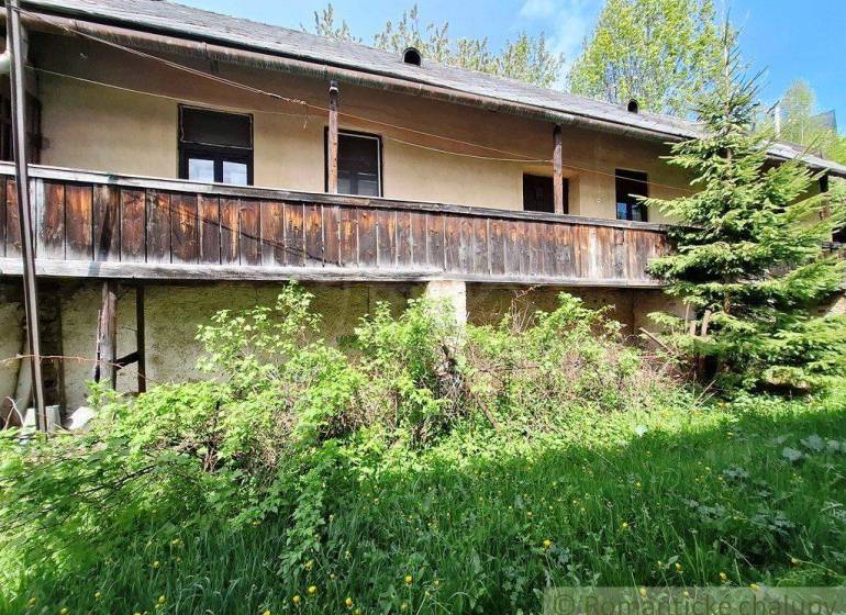 Ein Einfamilienhaus in Pohorelá mit einem älteren Holzbalkon und gepflegtem Grün.