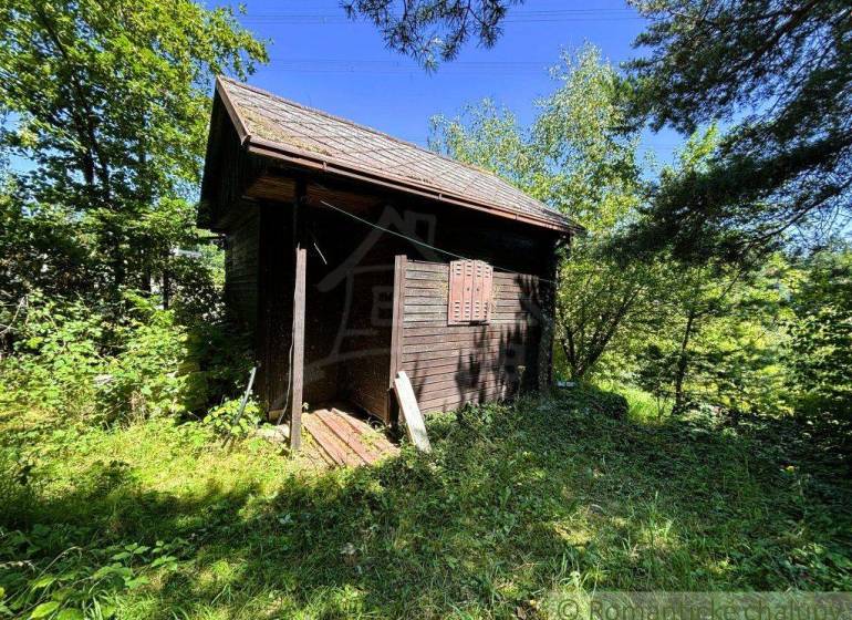 Eine Holzhütte umgeben von Grün in den Gärten von Malacky, der ideale Ort zum Entspannen.