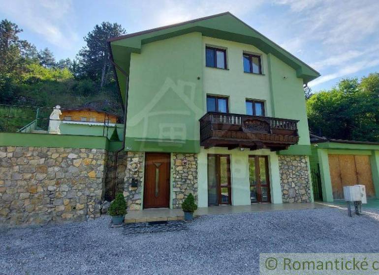 Ein Einfamilienhaus in Dobrá Voda mit Steindetails und einem Holzbalkon in einer natürlichen Szenerie.