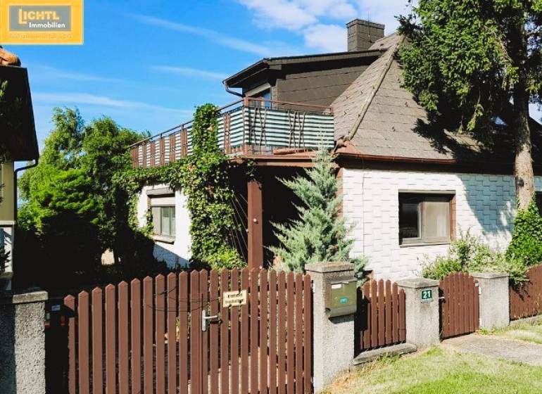 Ein Einfamilienhaus in Hundsheim mit einem Holzzaun, einer Terrasse und üppigem Grün.