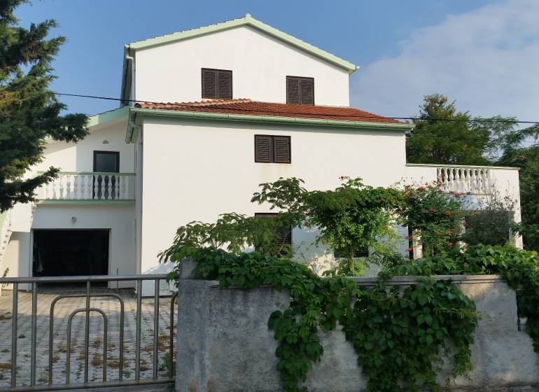 Ein Einfamilienhaus in Vrsi mit weißer Fassade und einer Terrasse, umgeben von Grün.