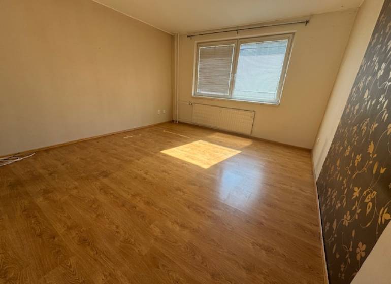 Ein Zimmer mit hellem Laminatboden und zwei Fenstern in einer 3-Zimmer-Wohnung.