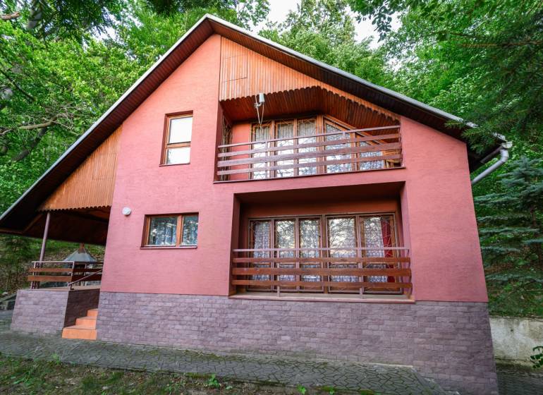 Holzhütte in Ružiná, umgeben von Grün und mit einer Terrasse im Obergeschoss.