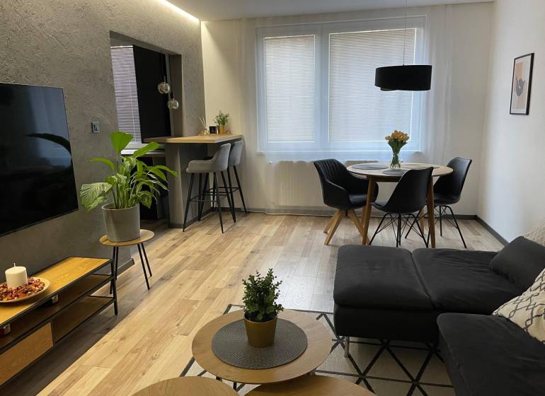 Wohnzimmer in einer 3-Zimmer-Wohnung mit Sofa, Esstisch und Fernseher.