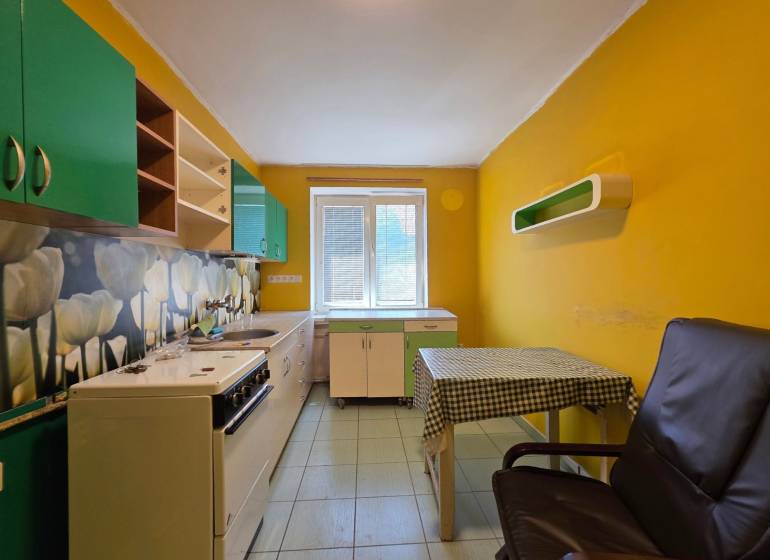 Küche mit gelben Wänden und grünen Schränken in einer 2-Zimmer-Wohnung.