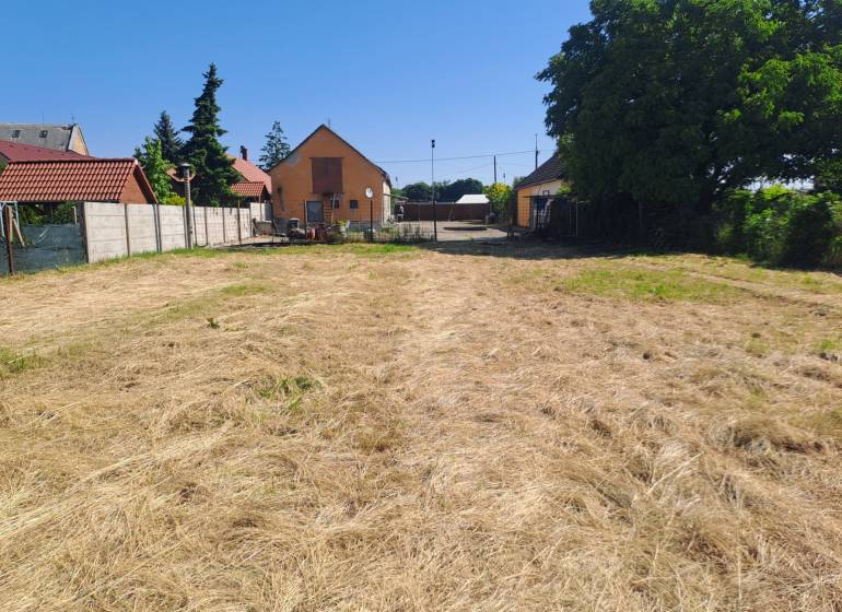 Ein Garten bei einem Einfamilienhaus in Sládkovičovo mit gepflegtem Rasen und einem Zaun.