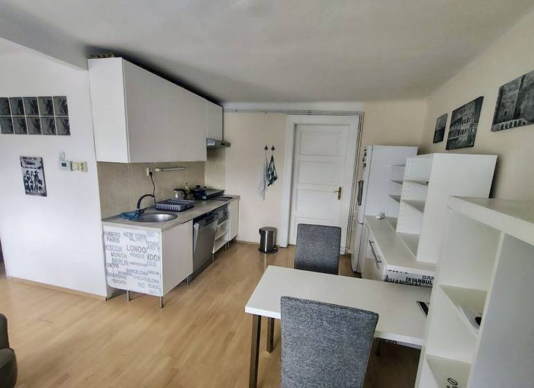 Küche in einer 2-Zimmer-Wohnung mit Esstisch, weißen Schränken und Holzboden.