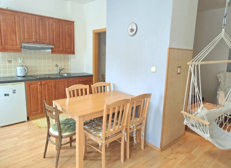 Küche mit Einbauschränken, Esstisch und Schaukelstuhl in einer 3-Zimmer-Wohnung.