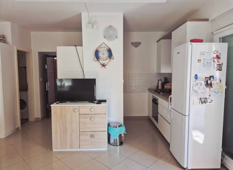Küche in einer 2-Zimmer-Wohnung mit Geräten, Schrank, Fernseher und Wanddekoration.