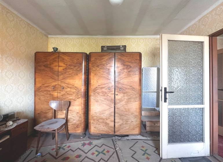 Retro-Möbel mit Holzschränken in einer 3-Zimmer-Wohnung mit Teppichboden und Tapeten.