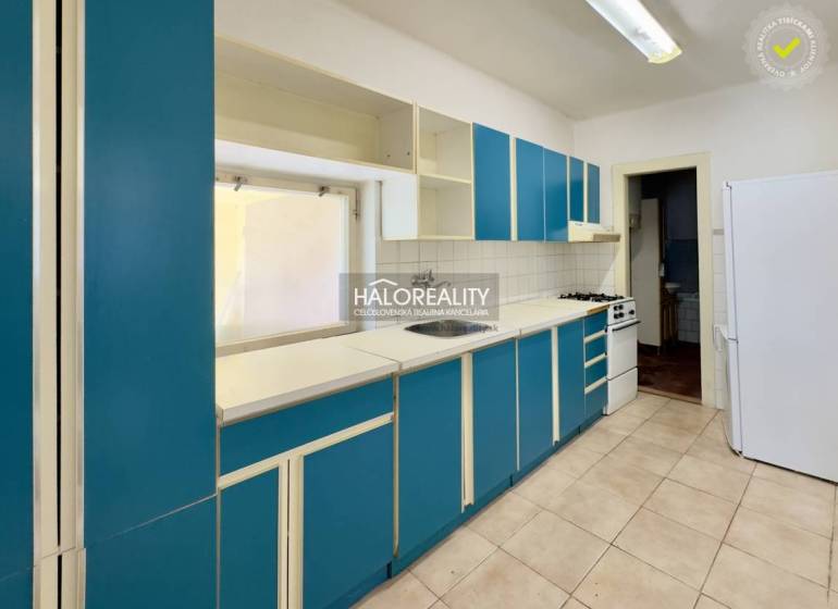 Küche in einem Einfamilienhaus mit blauen Schränken und weißen Geräten.