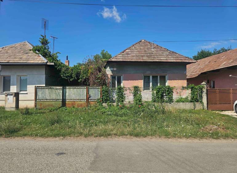 Ein Einfamilienhaus in Hronovce mit Garten und Tor, umgeben von Pflanzen.