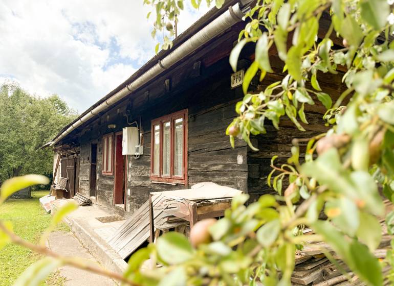 Eine Holzhütte in Papradno, umgeben von Natur, mit ländlicher Atmosphäre und grünem Rasen.