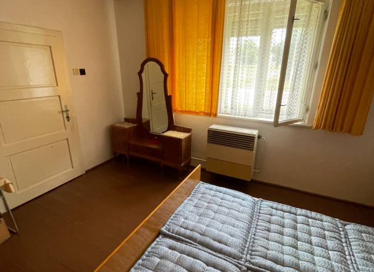Schlafzimmer im Einfamilienhaus mit Fenster, Spiegel und Bett mit gestepptem Matratze.