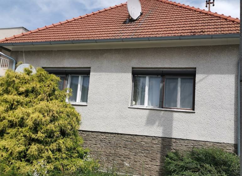 Ein Einfamilienhaus in Topoľčianky mit einem Satteldach und einer Satellitenschüssel.