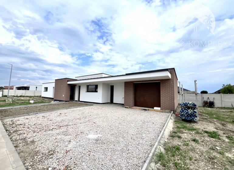 Ein Einfamilienhaus in Miloslavov mit Ziegelverkleidung und großem Parkplatz, klarer Himmel.