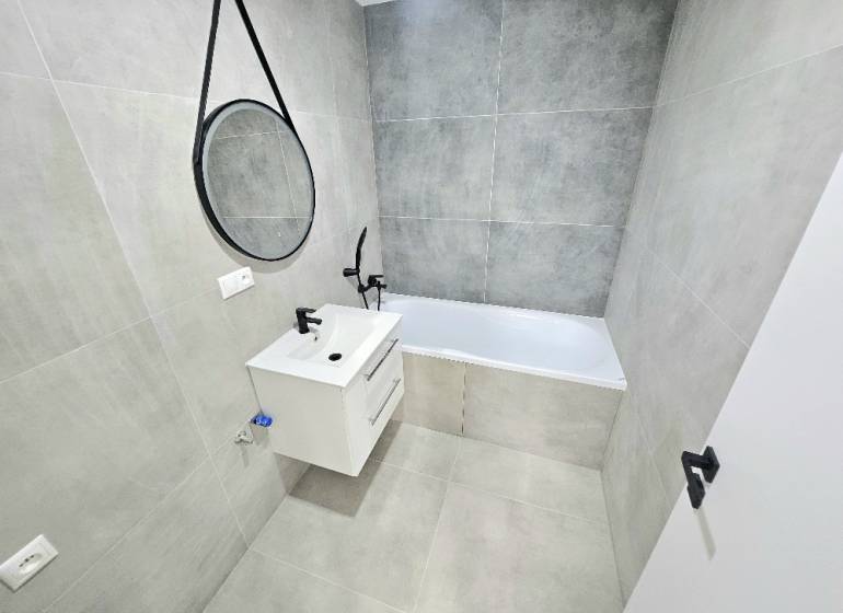 Badezimmer in einer 3-Zimmer-Wohnung mit Badewanne, Waschbecken und Spiegel an der Wand.