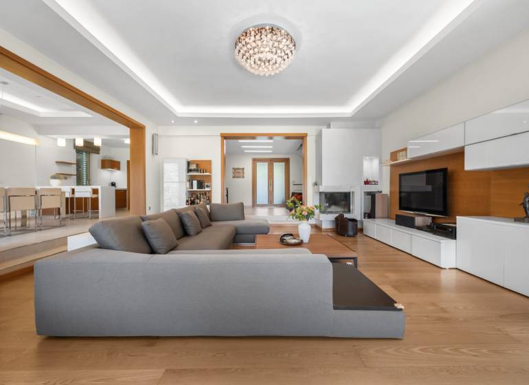 Wohnzimmer in einem Einfamilienhaus mit großem grauem Sofa und weißen Möbeln.