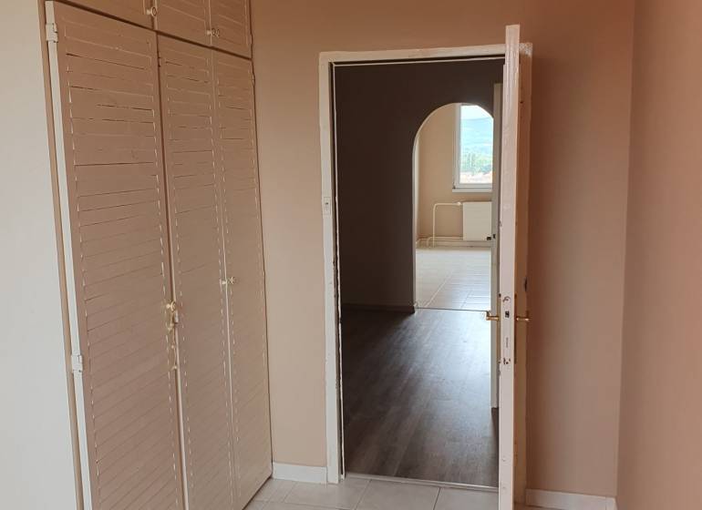 Innenraum einer 3-Zimmer-Wohnung mit Fliesen, Garderobenwand und Durchgang zu einem weiteren Raum.