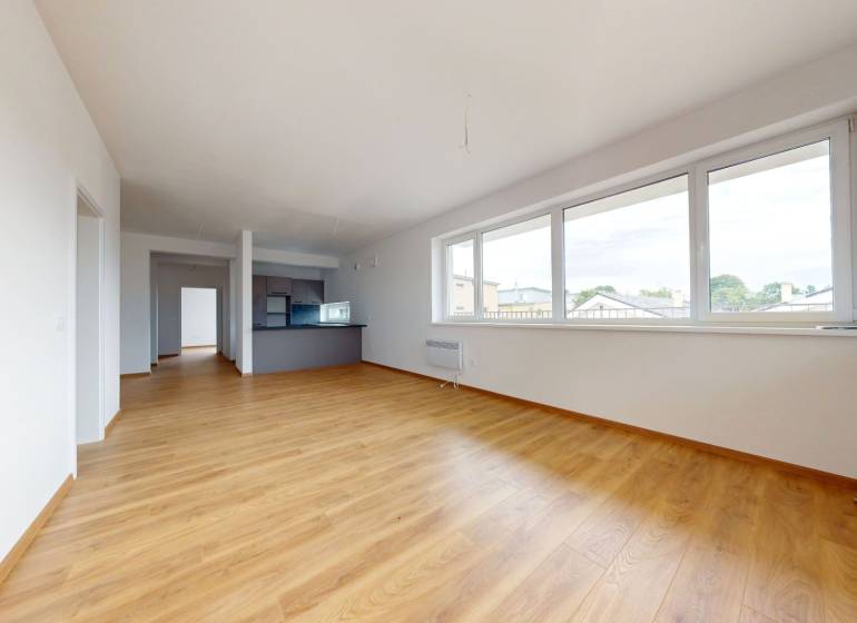 Geräumiges Wohnzimmer mit Holzboden und großen Fenstern in einer 3-Zimmer-Wohnung.