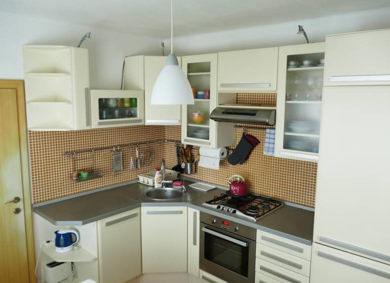 Küche in einer 3-Zimmer-Wohnung mit Küchenzeile, Geräten und orangefarbenen Fliesen.