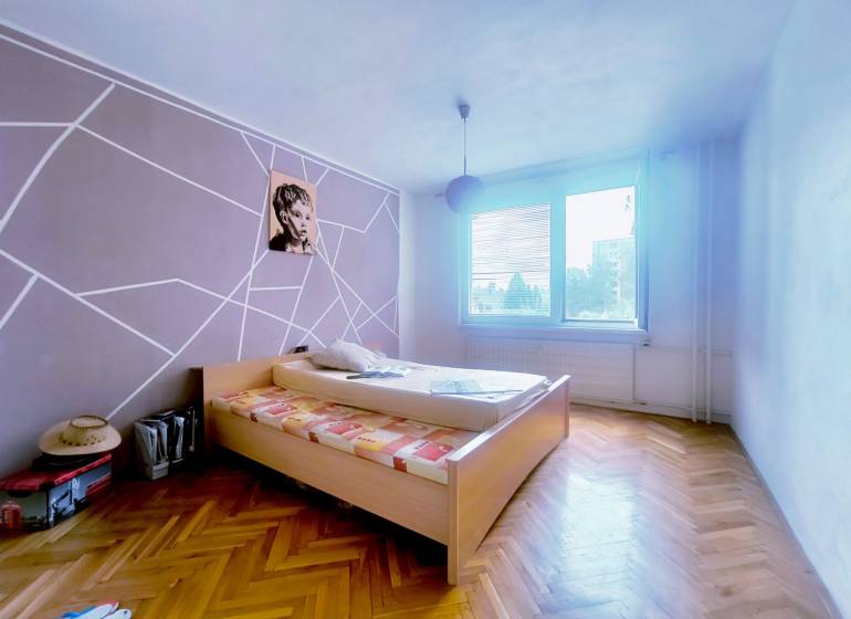 Schlafzimmer in einer 3-Zimmer-Wohnung mit Holzboden und auffälliger Wanddekoration.