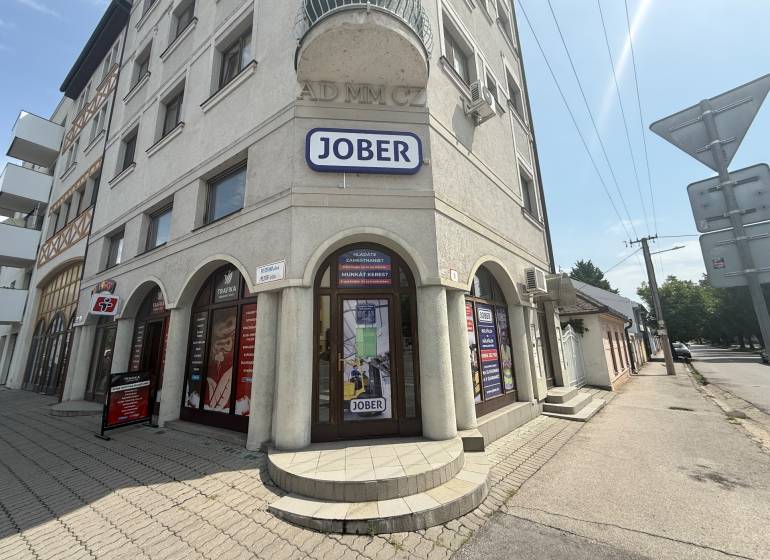 Geschäftsräume in Komárno in der Petőfi-Straße mit sonniger Fassade und Werbeschildern.