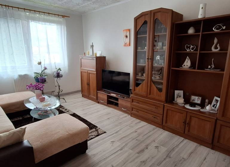 Wohnzimmer in einer 3-Zimmer-Wohnung mit Sofa, Schrank und Fernseher, helle Dekoration.