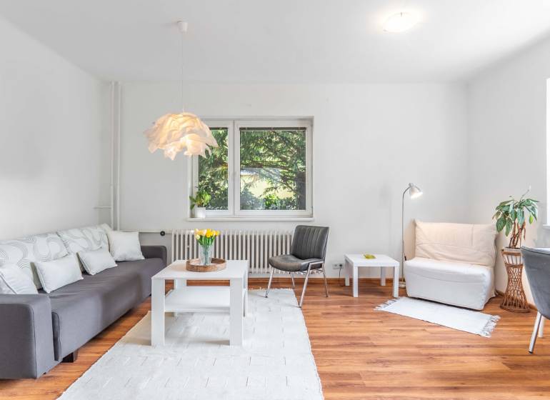 Wohnzimmer einer Zweizimmerwohnung mit Sofa und Holzboden, helle Dekoration.