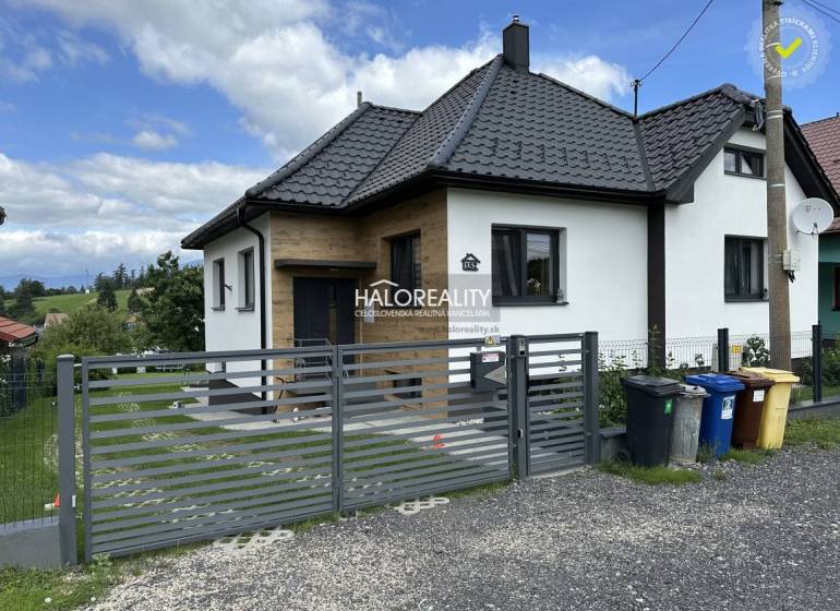 Ein Einfamilienhaus in Liptovský Hrádok mit modernem Schrägdach und Tor, daneben stehen Mülltonnen.
