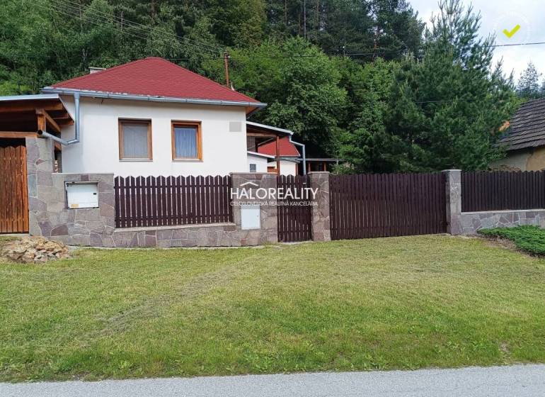 Ein Ferienhaus in Helcmanovce mit einem Holzzaun und gepflegtem Rasen, umgeben von Grün.