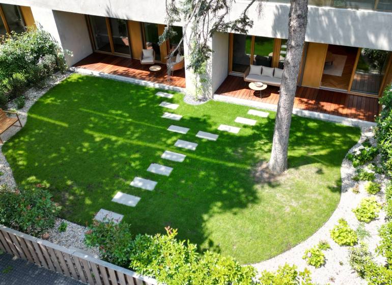 Gartenterrasse einer 4-Zimmer-Wohnung mit Rasen und Holzmöbeln.